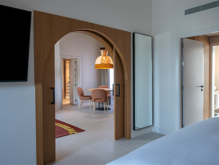 An open arch doorway leads onto a room with a circular table underneath a beautiful yellow light shade