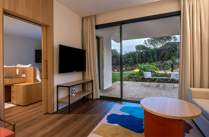 Elegante habitación de hotel que presenta una gran puerta corrediza de vidrio que mejora la luz natural y el acceso al exterior.
