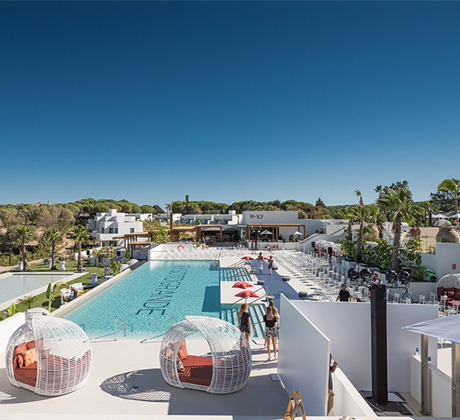 Birds eye view of a large pool with chairs and equipment being set up one side