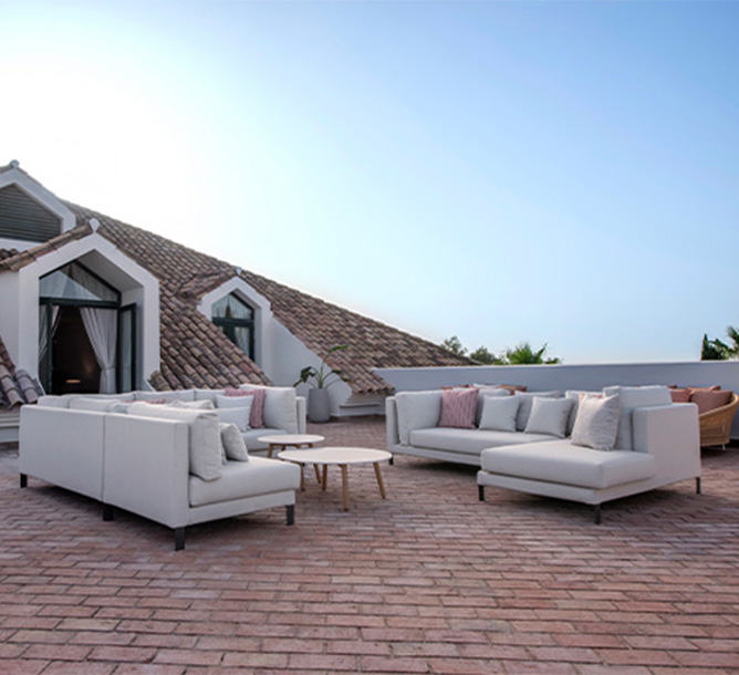 A large brick terrace with white couches and wooden coffee tables 