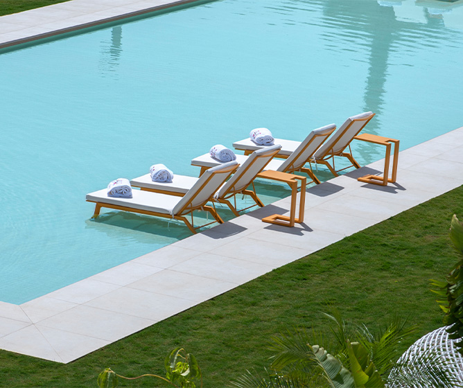 Four white lougers sitting on the water of a pool. 