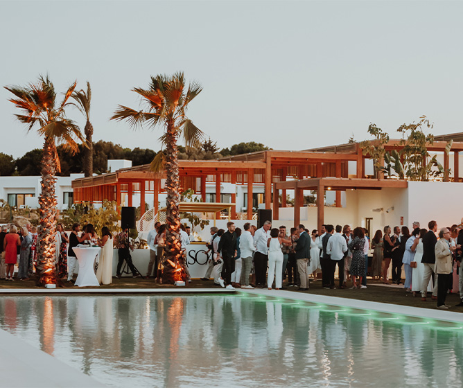 A large crowd mingling beside a pool 