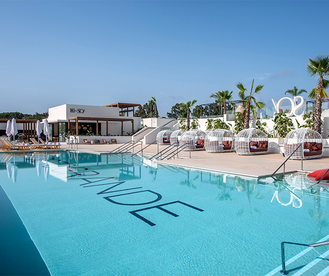 A large clear blue pool with 'Sotogrande' visible at the bottom. Circular shaped booths and palm trees surrounding the pool