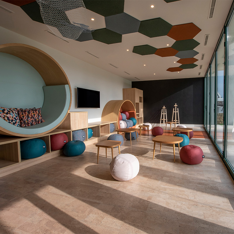 A large kids playroom with cushions, beanbags and wooden tables