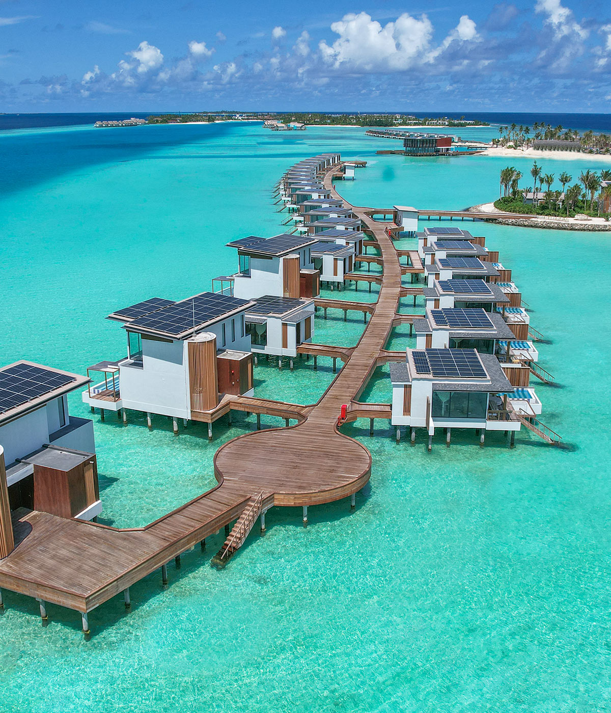 Villas arranged along a snaking wooden pier out across the blue tropical water