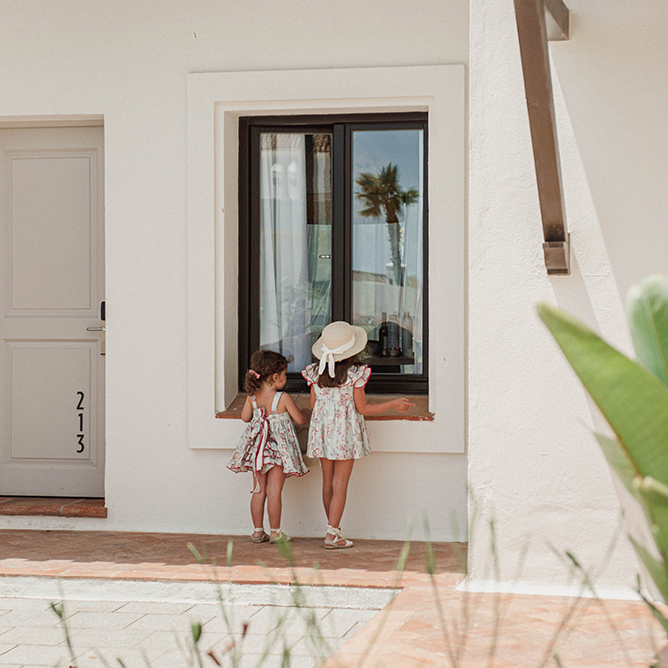 Two kids peer through a window at the Kids Club