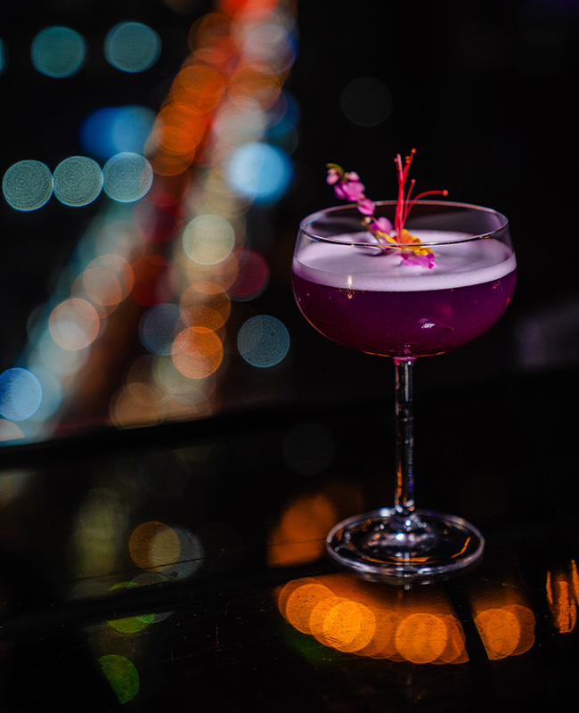 A delicious looking purple cocktail sits of a table.