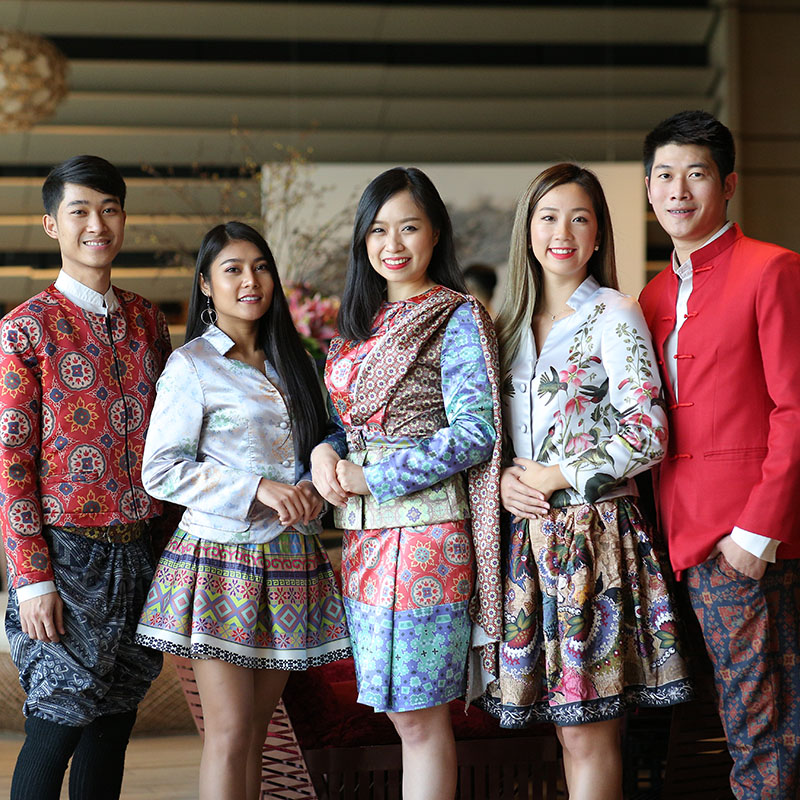Members of the SO/ Bangkok staff pose smiling, dressed in beautifully designed uniforms.
