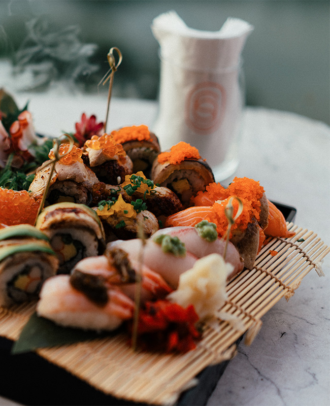 A variety of sushi sit on a sushi rolling mat.