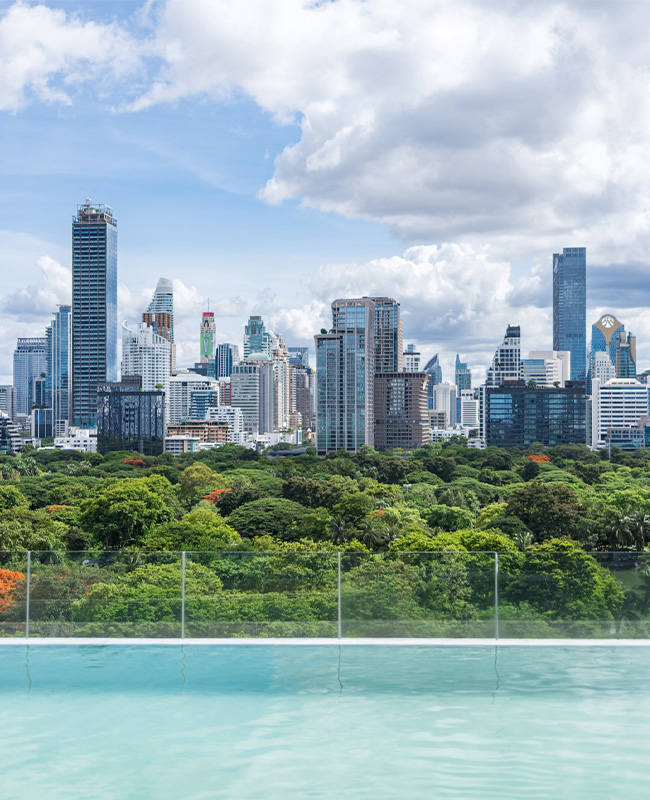 An infinity pool overlooks Bangkok's Lumpini Park and skyline.