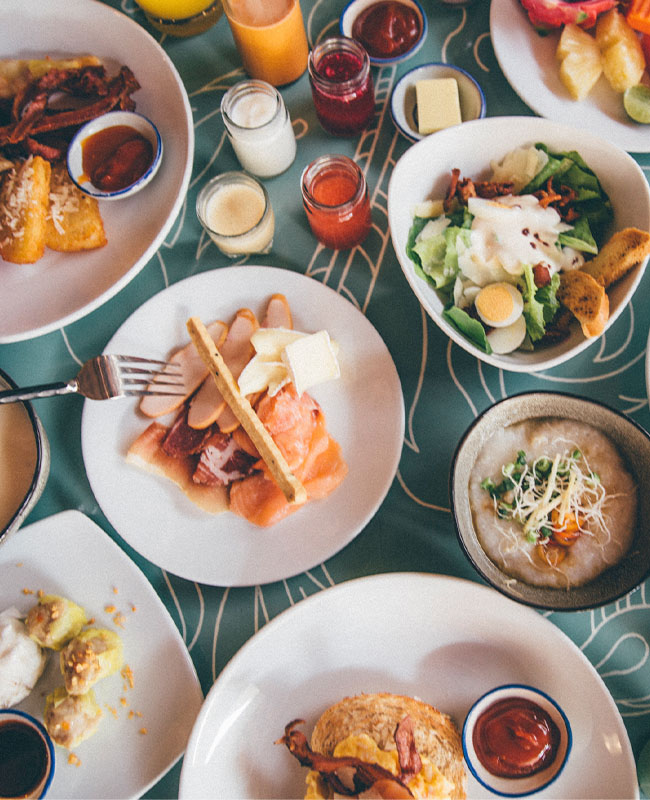 A variety of brunch dishes on a table, including smoked salmon on toast, a fresh salad, mashed potatoes, and dipping sauces, creating a vibrant spread.