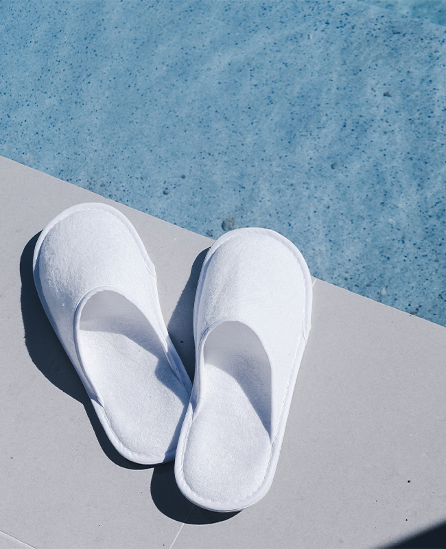 A pair of white slippers next to the pool.