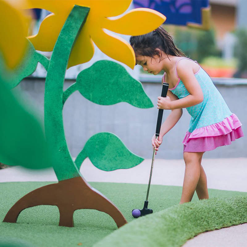 A little girl playing mini golf