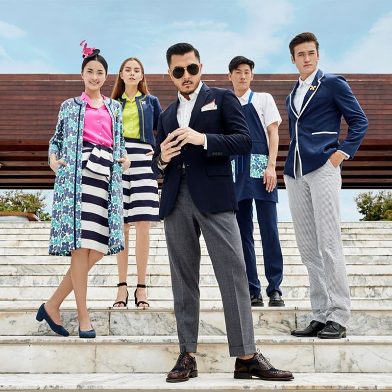 Five stylishly dressed individuals stand confidently on steps, set against a modern building. They convey sophistication and teamwork.
