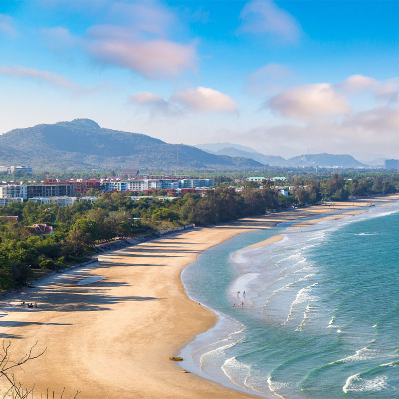 A birds eye view of a beautiful beach, clear blue water and mountains in the distance