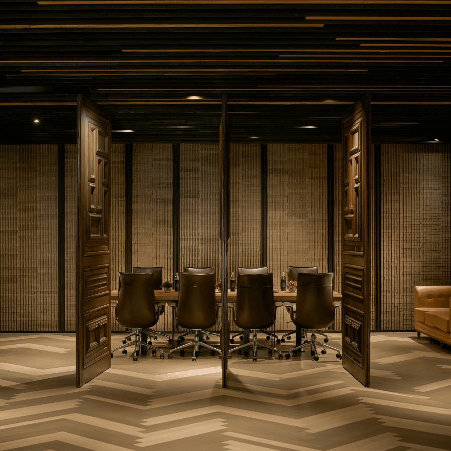 Private meeting room with elegant wooden interiors, boardroom setup, and stylish partition doors creating an intimate, design-led workshop.