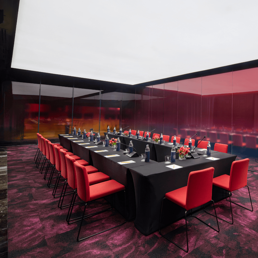 Modern meeting room with U-shape conference setup, red designer chairs, and a bold, design-led interior for corporate events and presentations.