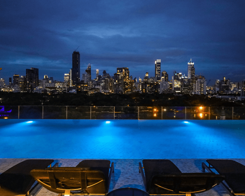 http://Nighttime%20view%20of%20a%20pool%20with%20a%20vibrant%20city%20skyline%20illuminated%20in%20the%20background.