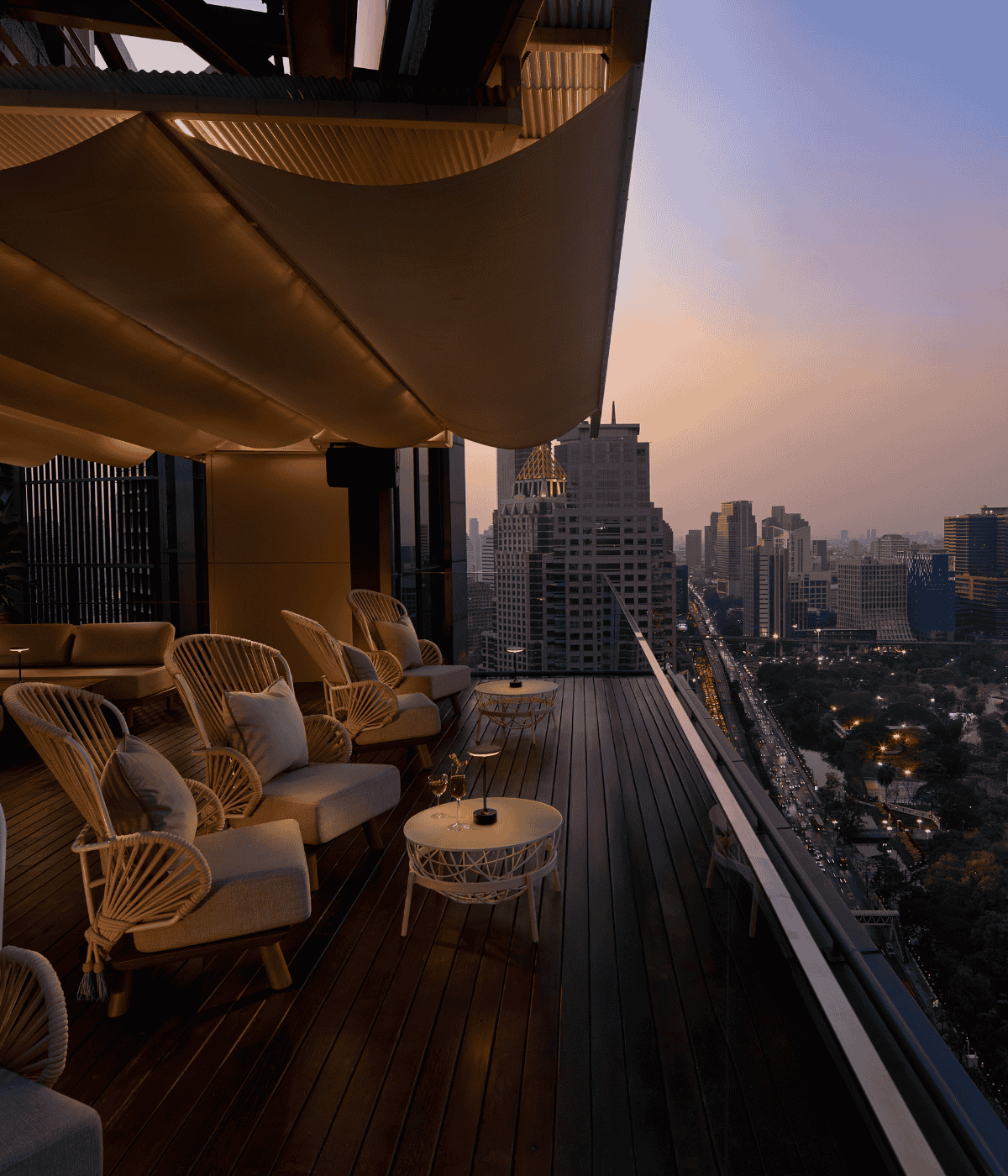 Iris Terrace at Iris & Wild Iris rooftop, with stylish lounge seating and sunset views over Lumphini Park and Bangkok’s skyline.