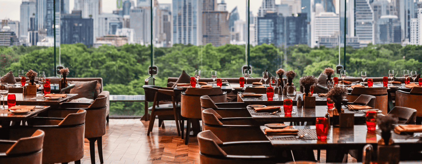A restaurant interior featuring large windows showcasing a panoramic view of the city skyline.