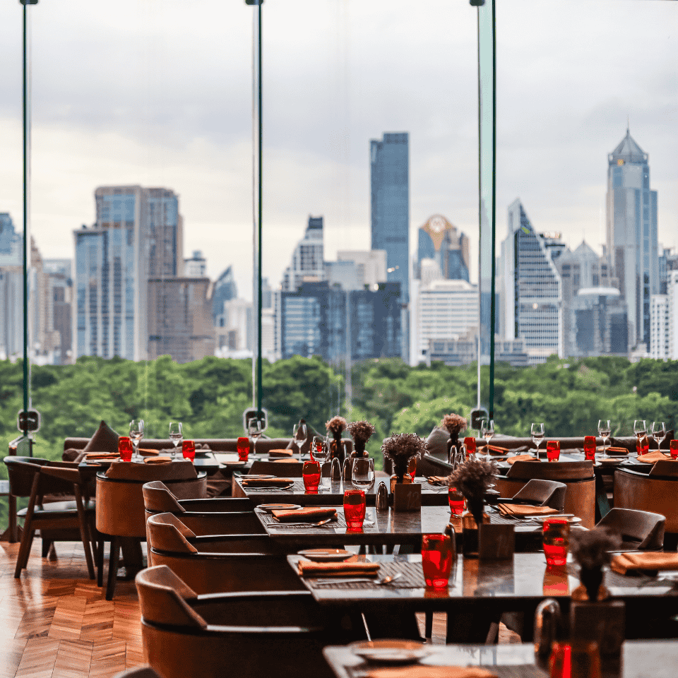 A restaurant interior featuring large windows showcasing a panoramic view of the city skyline.