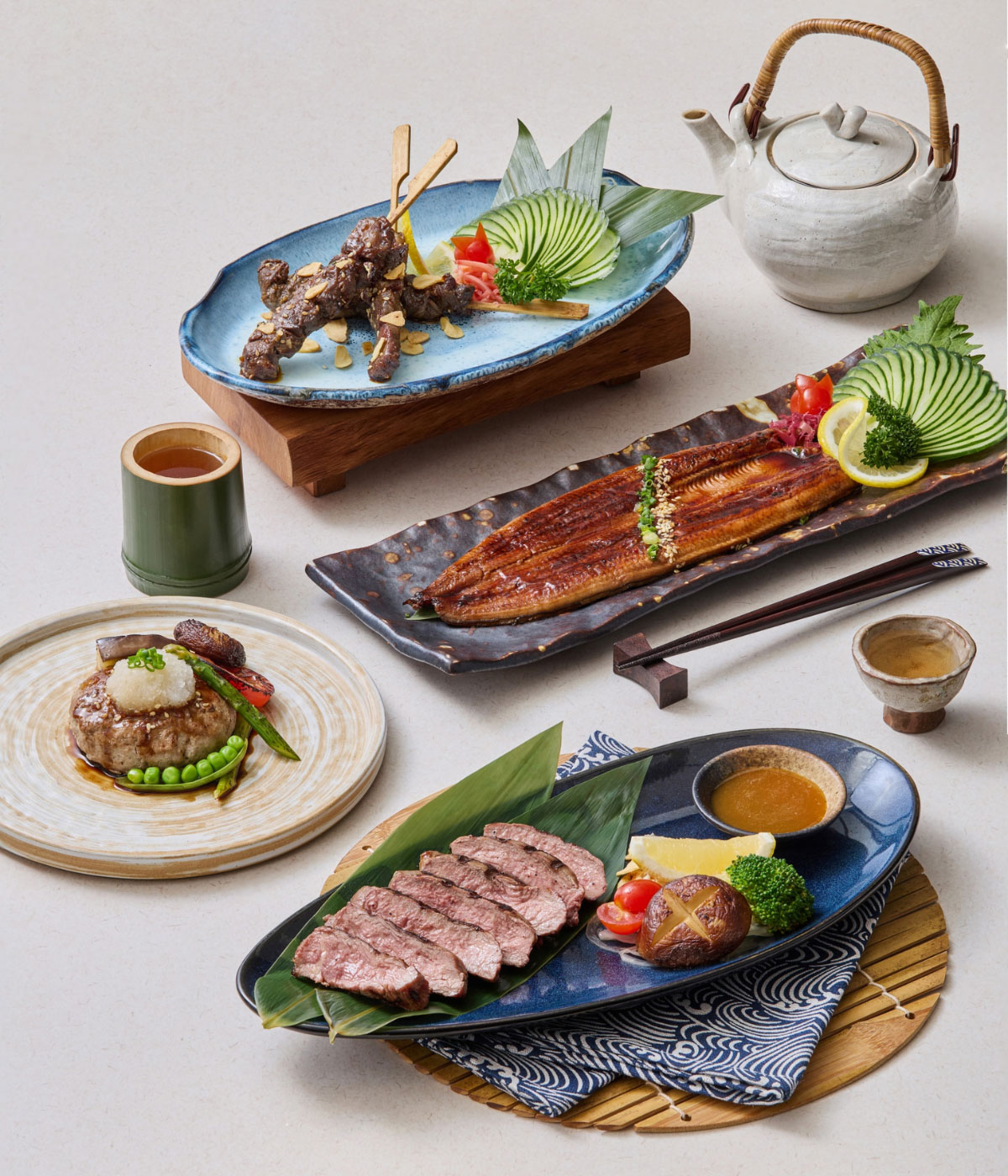 Selection of fine Japanese dishes including grilled eel (Unagi), sliced Wagyu beef, Yakitori skewers, and a hamburger steak served on ceramic tableware.