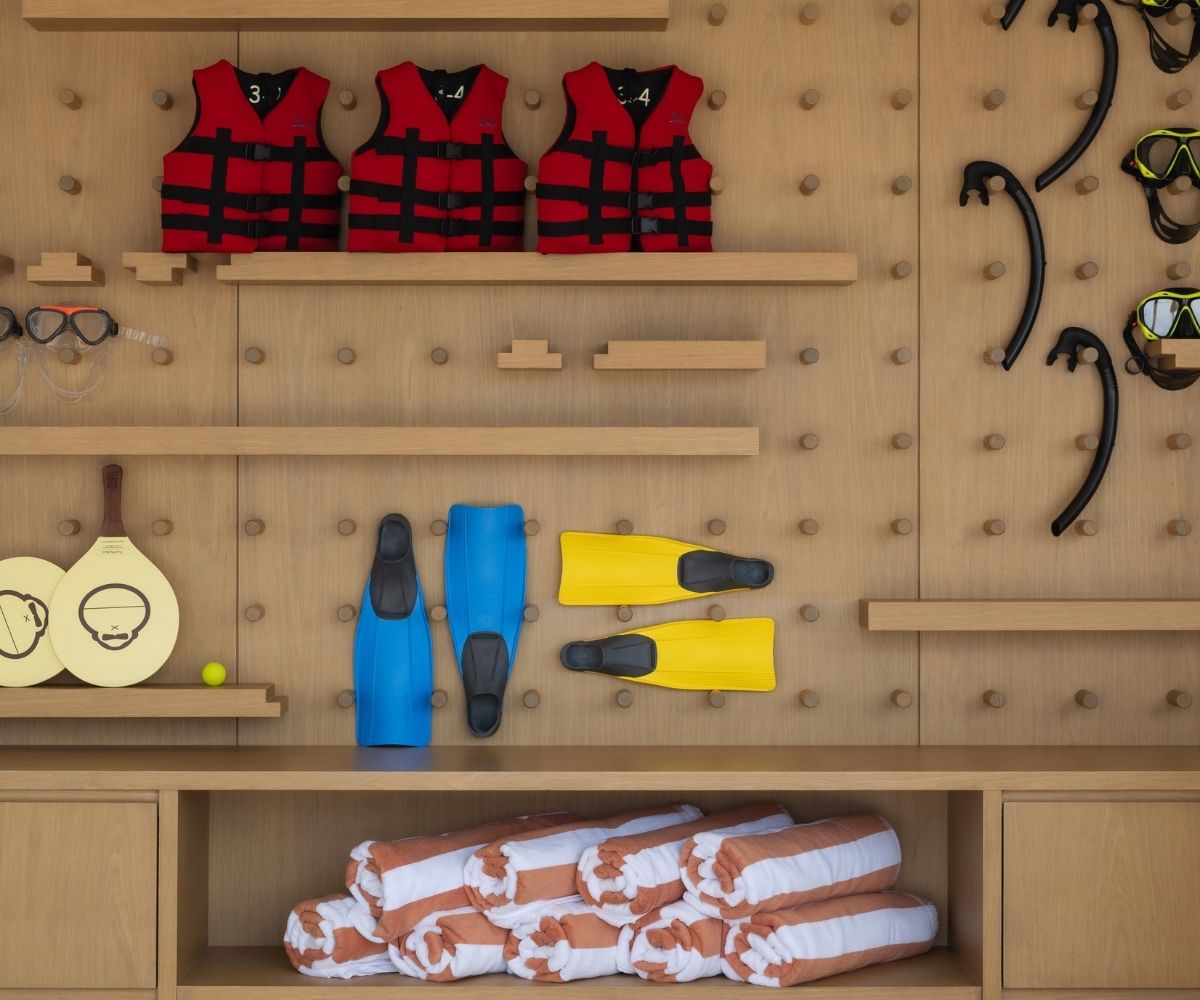 A diverse assortment of items on a shelf, including life jackets, water fins, scuba masks, and towels for water activities.