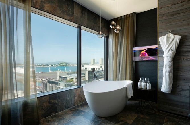 http://Elegant%20bathroom%20featuring%20a%20freestanding%20tub,%20stunning%20bay%20view,%20modern%20decor,%20and%20a%20TV,%20with%20a%20plush%20robe%20hanging%20nearby.