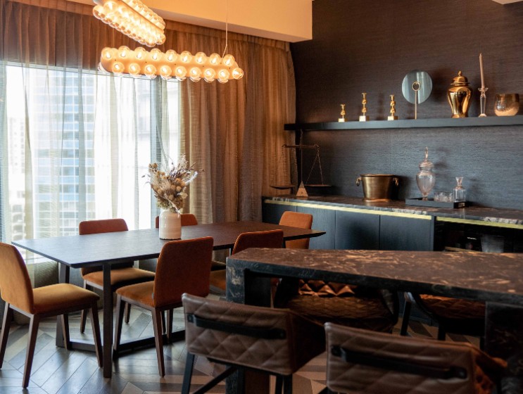 Modern dining area featuring a dark wood table, stylish chairs, large windows draped with curtains, and decorative shelves.