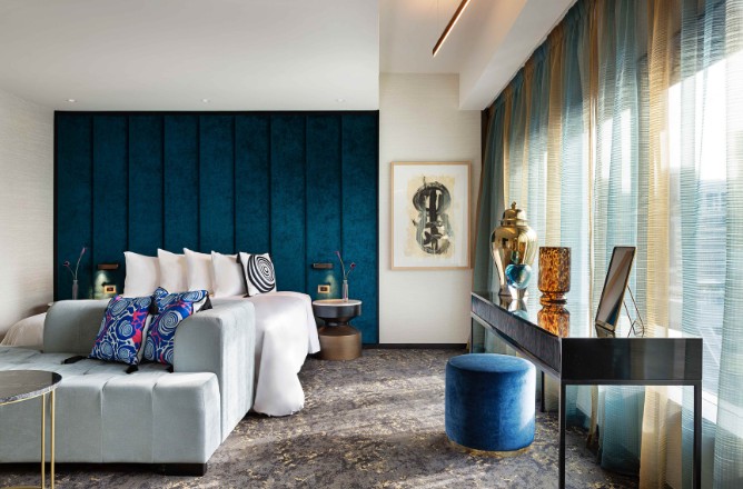 http://A%20stylish%20hotel%20room%20featuring%20a%20teal%20accent%20wall,%20plush%20bedding,%20modern%20decor,%20and%20elegant%20light%20curtains.
