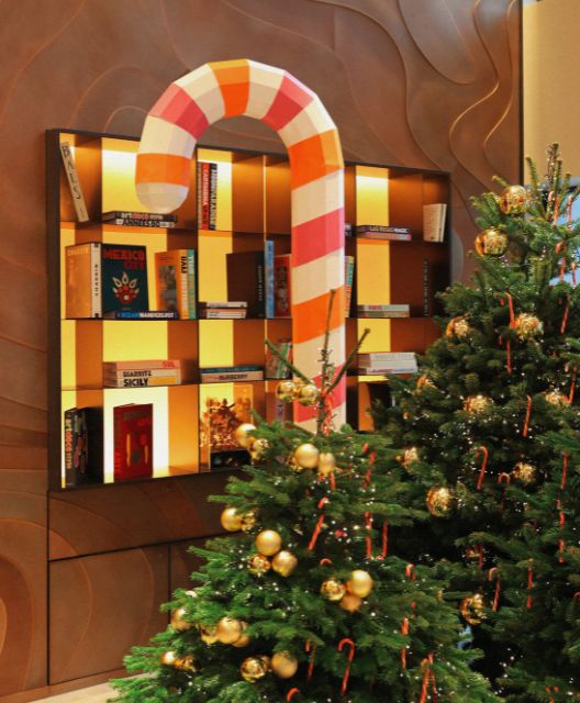 Festive scene with two decorated Christmas trees featuring gold ornaments and candy canes, and a large, striped candy cane in the background.
