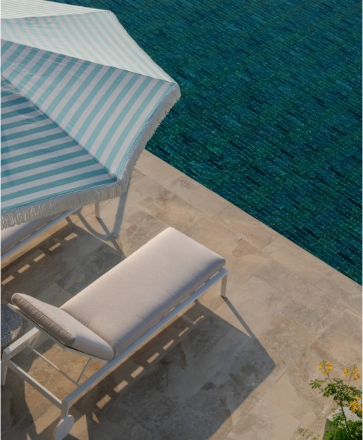http://A%20serene%20poolside%20scene%20with%20a%20padded%20lounger%20under%20a%20blue%20and%20white%20striped%20umbrella.%20The%20pool's%20deep%20blue%20water%20contrasts%20the%20light%20stone%20tiles.