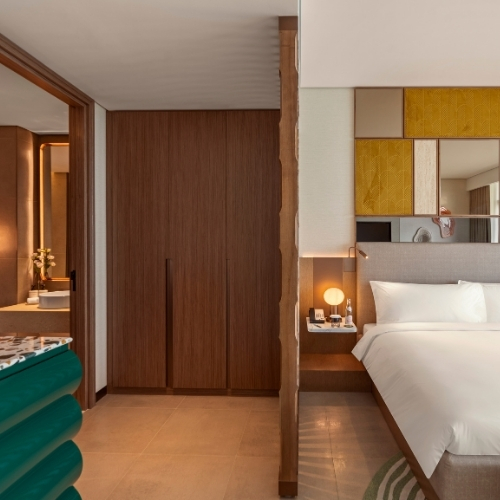 http://Modern%20hotel%20room%20with%20sleek%20design.%20Features%20a%20cozy%20bed,%20stylish%20wall%20accents,%20wooden%20closet,%20and%20a%20glimpse%20of%20a%20lit%20bathroom,%20exuding%20warmth%20and%20comfort.