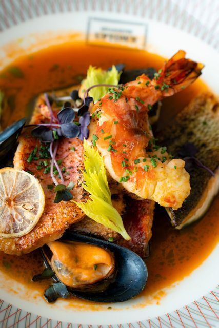 http://Gourmet%20seafood%20dish%20with%20shrimp,%20mussels,%20and%20lemon%20slices%20in%20rich%20broth,%20garnished%20with%20herbs%20and%20edible%20flowers,%20on%20an%20elegant%20plate.