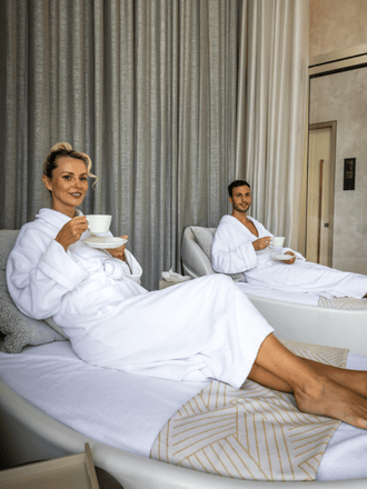 http://A%20man%20and%20woman%20in%20white%20robes%20relax%20on%20lounge%20chairs,%20sipping%20tea%20in%20a%20serene%20spa%20setting%20with%20neutral%20tones%20and%20soft%20lighting.