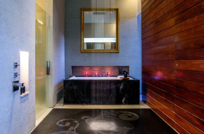 http://A%20luxurious%20spa%20bathroom%20featuring%20a%20large%20rain%20shower%20head%20above%20a%20black%20marble%20bathtub,%20warm%20mood%20lighting,%20and%20a%20golden%20framed%20mirror,%20creating%20a%20serene%20atmosphere.