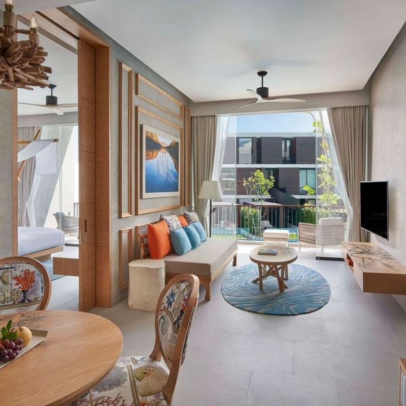 http://Bright%20and%20airy%20modern%20room%20featuring%20a%20cozy%20seating%20area,%20decorative%20art,%20and%20an%20inviting%20bedroom%20beyond,%20accented%20with%20vibrant%20pillows.