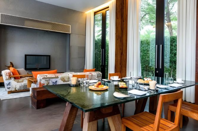 http://A%20modern%20luxury%20villa%20interior%20showing%20a%20green%20marble%20dining%20table%20set%20for%20breakfast,%20with%20wooden%20chairs,%20next%20to%20large%20glass%20doors%20opening%20to%20a%20lush%20garden.