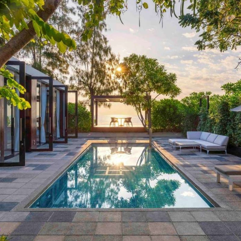http://A%20serene%20outdoor%20scene%20featuring%20a%20turquoise%20pool%20beside%20a%20modern%20house%20with%20glass%20doors.%20A%20cozy%20patio%20area%20and%20lush%20greenery%20enhance%20the%20tranquil%20vibe.