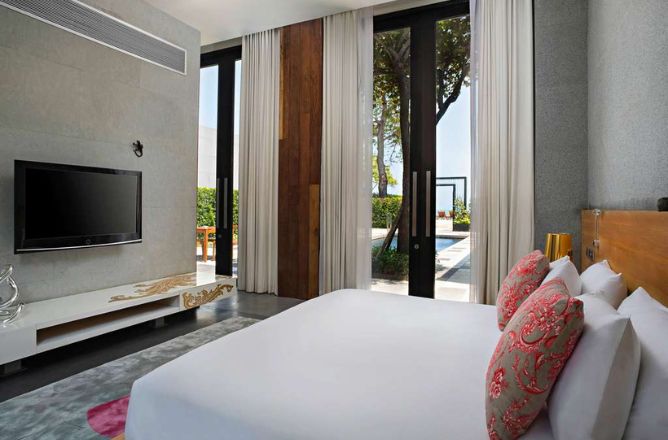 http://A%20sleek%20hotel%20bedroom%20with%20a%20large%20white%20bed,%20modern%20entertainment%20unit,%20and%20floor-to-ceiling%20glass%20doors%20providing%20direct%20views%20of%20a%20private%20pool%20and%20lush%20surroundings.