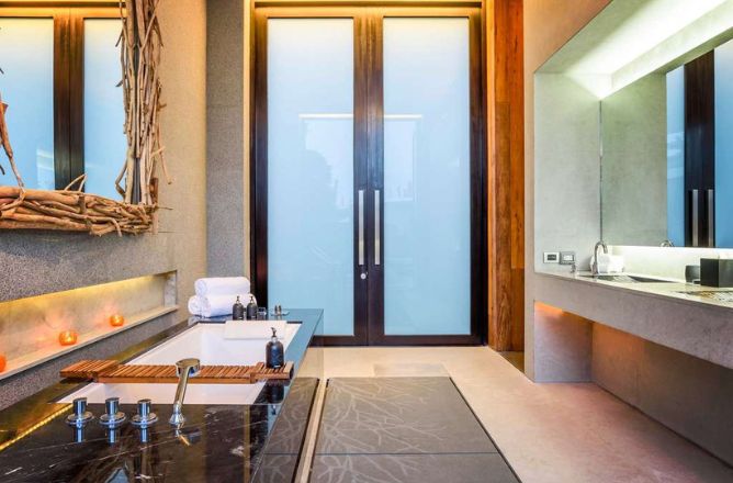 http://A%20luxurious%20spa-like%20bathroom%20featuring%20a%20deep%20soaking%20tub%20with%20a%20dark%20marble%20surround,%20a%20modern%20vanity%20with%20two%20sinks,%20and%20frosted%20glass%20doors%20leading%20outside.