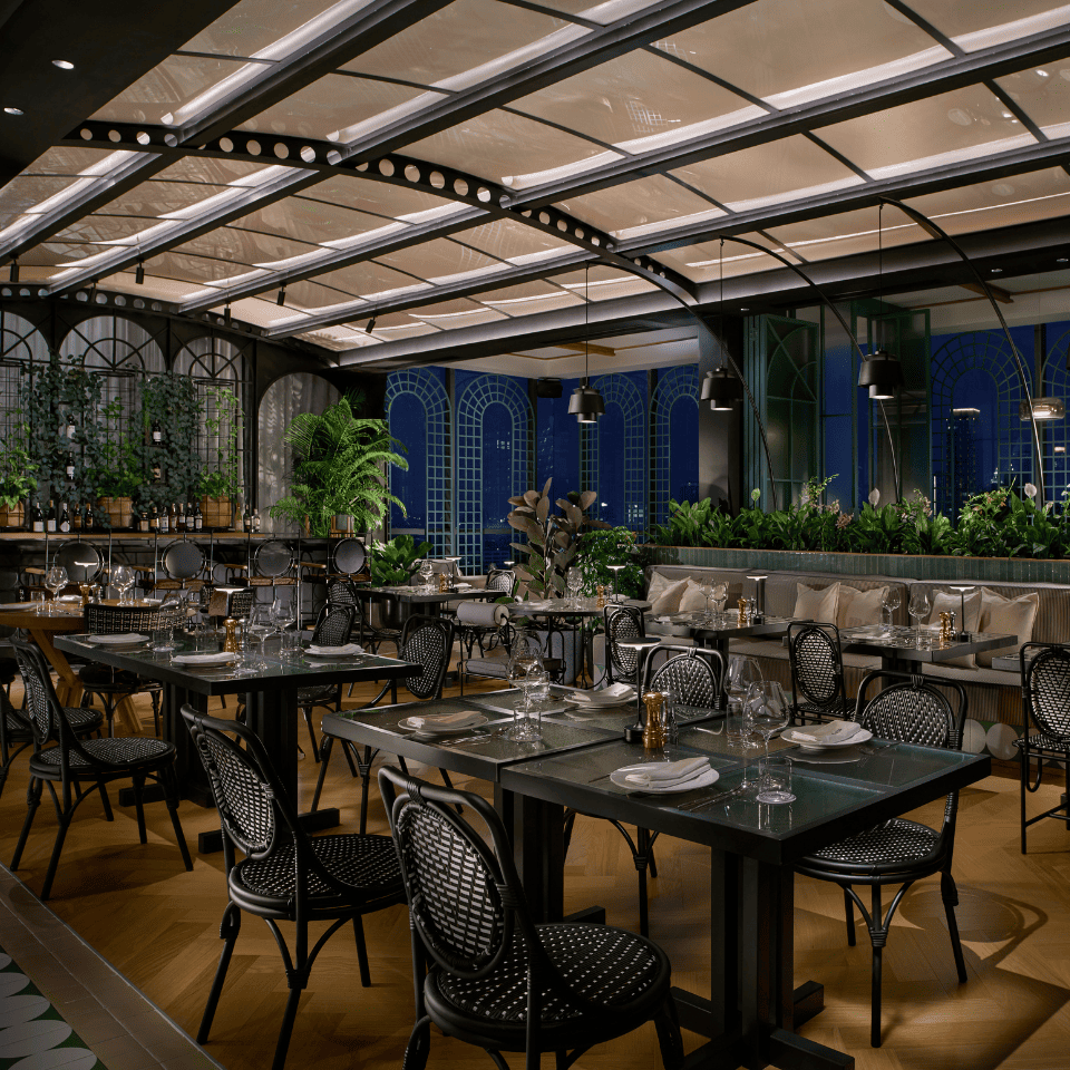 Elegant restaurant interior with stylish tables, plush seating, greenery, and decorative lighting, creating a warm, inviting atmosphere.
