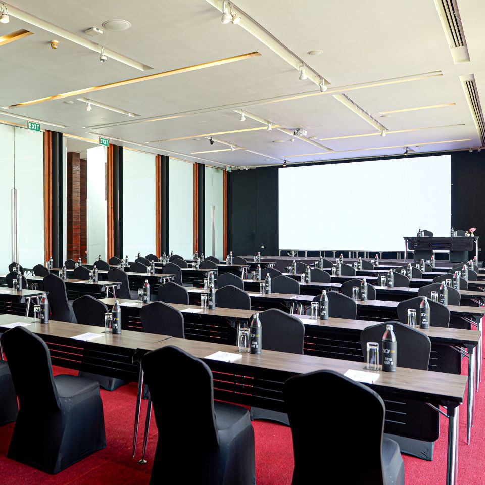 Corporate meeting space configured in a U-shape with black table linens, seating, and a large presentation screen at SO/ Sofitel Hua Hin