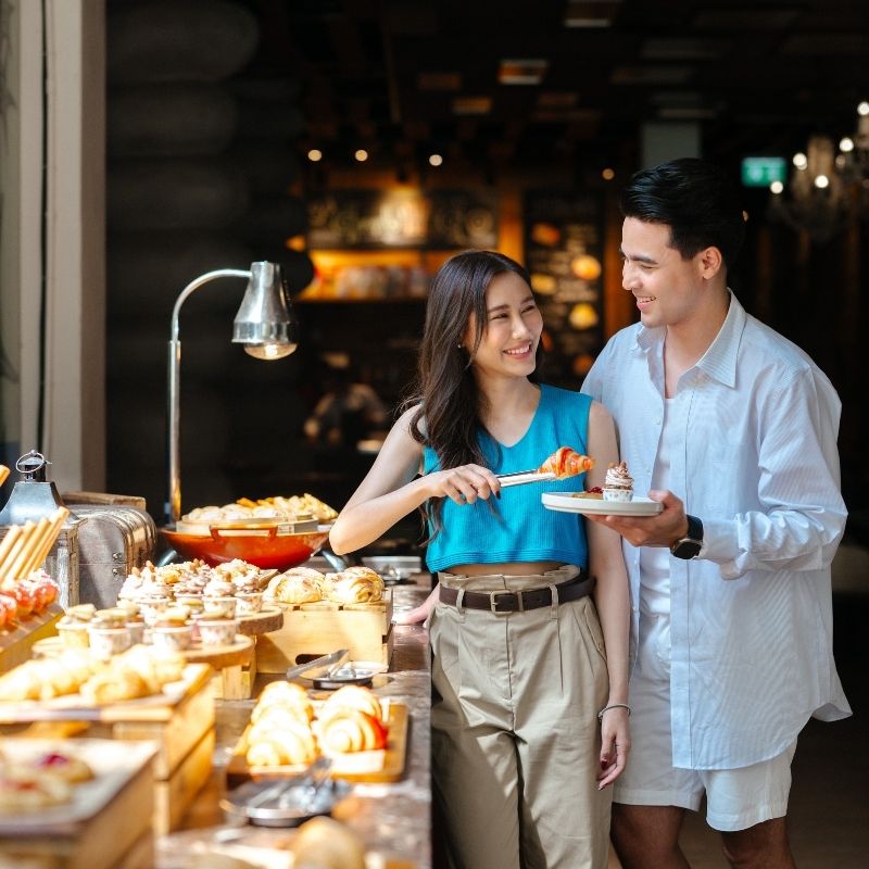 Couple selecting fresh pastries from the breakfast buffet at White Oven restaurant at SO/ Sofitel Hua Hin