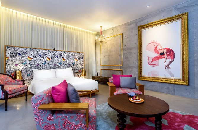 http://A%20stylish%20hotel%20room%20with%20floral-patterned%20furniture,%20a%20modern%20bed,%20and%20a%20large%20framed%20artwork%20of%20a%20dancer.%20Warm%20lighting%20creates%20a%20cozy%20ambiance.