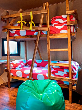 http://A%20cozy%20room%20features%20wooden%20bunk%20beds%20with%20vibrant%20red%20and%20white%20polka-dot%20bedding.%20A%20green%20beanbag%20sits%20on%20a%20warm%20wooden%20floor%20by%20a%20small%20window.