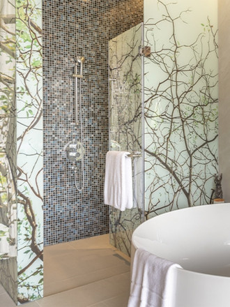 http://Modern%20bathroom%20with%20a%20nature-inspired%20theme;%20features%20a%20mosaic-tiled%20shower%20and%20frosted%20glass%20walls%20with%20twig%20patterns.%20A%20white%20towel%20hangs%20on%20the%20door.
