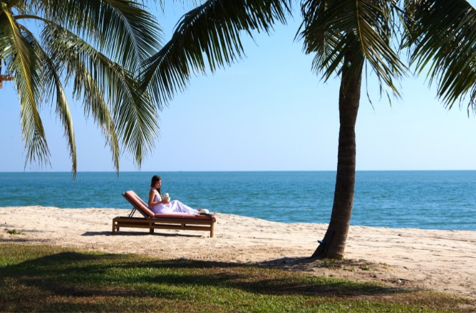 http://A%20person%20relaxes%20on%20a%20sun%20lounger%20under%20palm%20trees%20at%20a%20tranquil%20beach,%20looking%20towards%20the%20calm%20blue%20sea%20under%20a%20clear%20sky,%20conveying%20peaceful%20solitude.