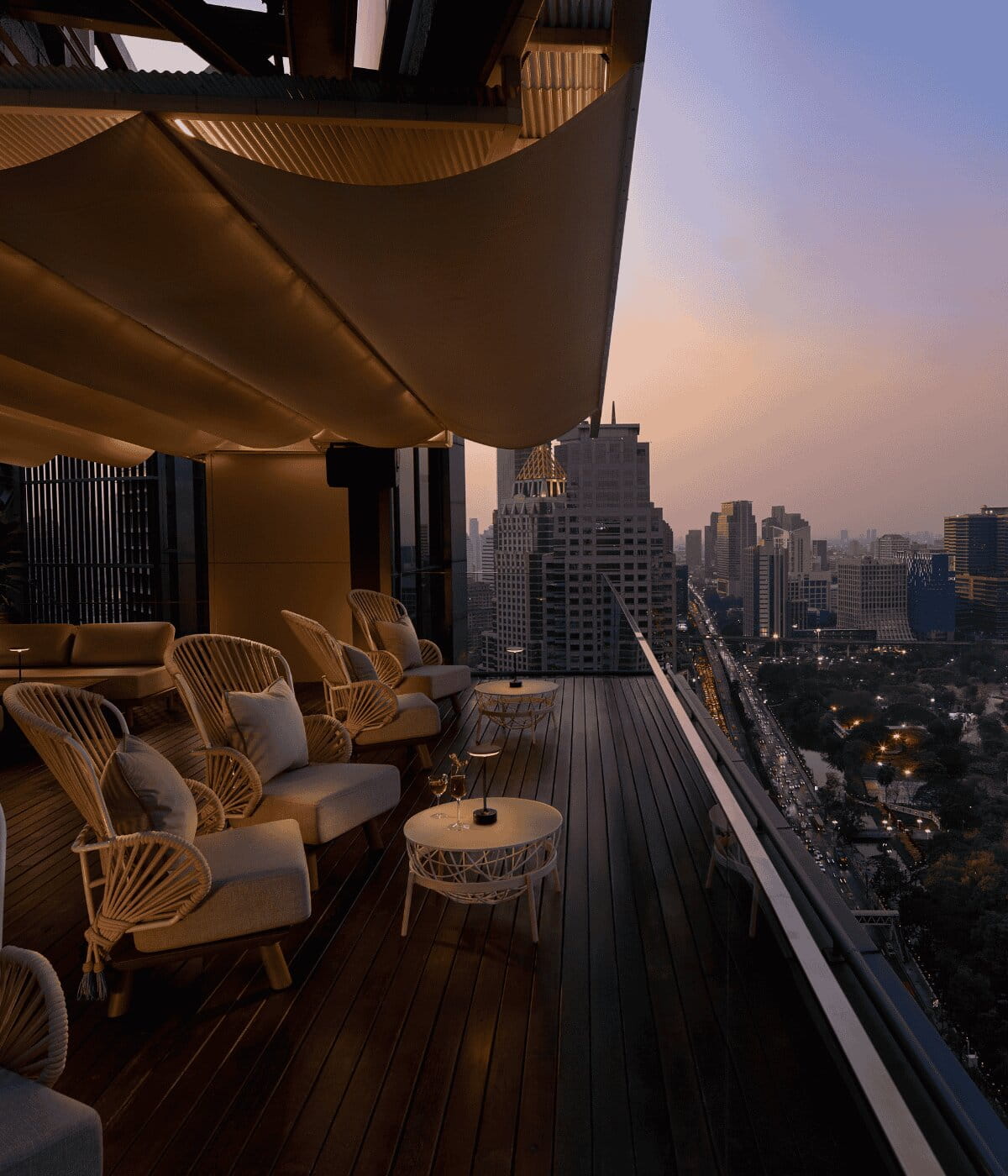 Iris Terrace at Iris & Wild Iris rooftop, with stylish lounge seating and sunset views over Lumphini Park and Bangkok’s skyline.