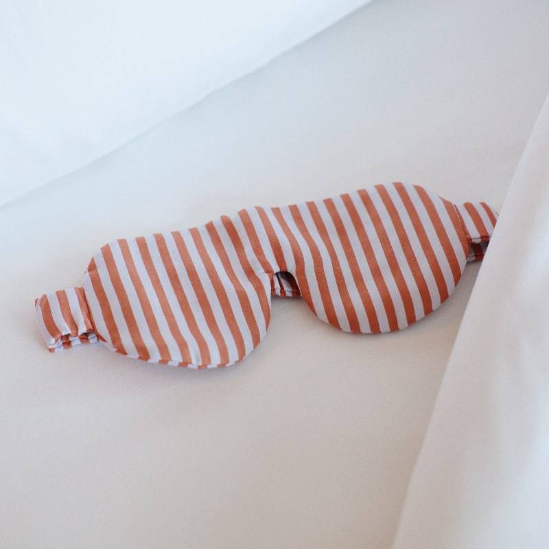 A pair of striped eye masks resting on a neatly made bed, showcasing their vibrant colors and patterns.